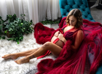 Woman in red tulle robe holding pregnant belly