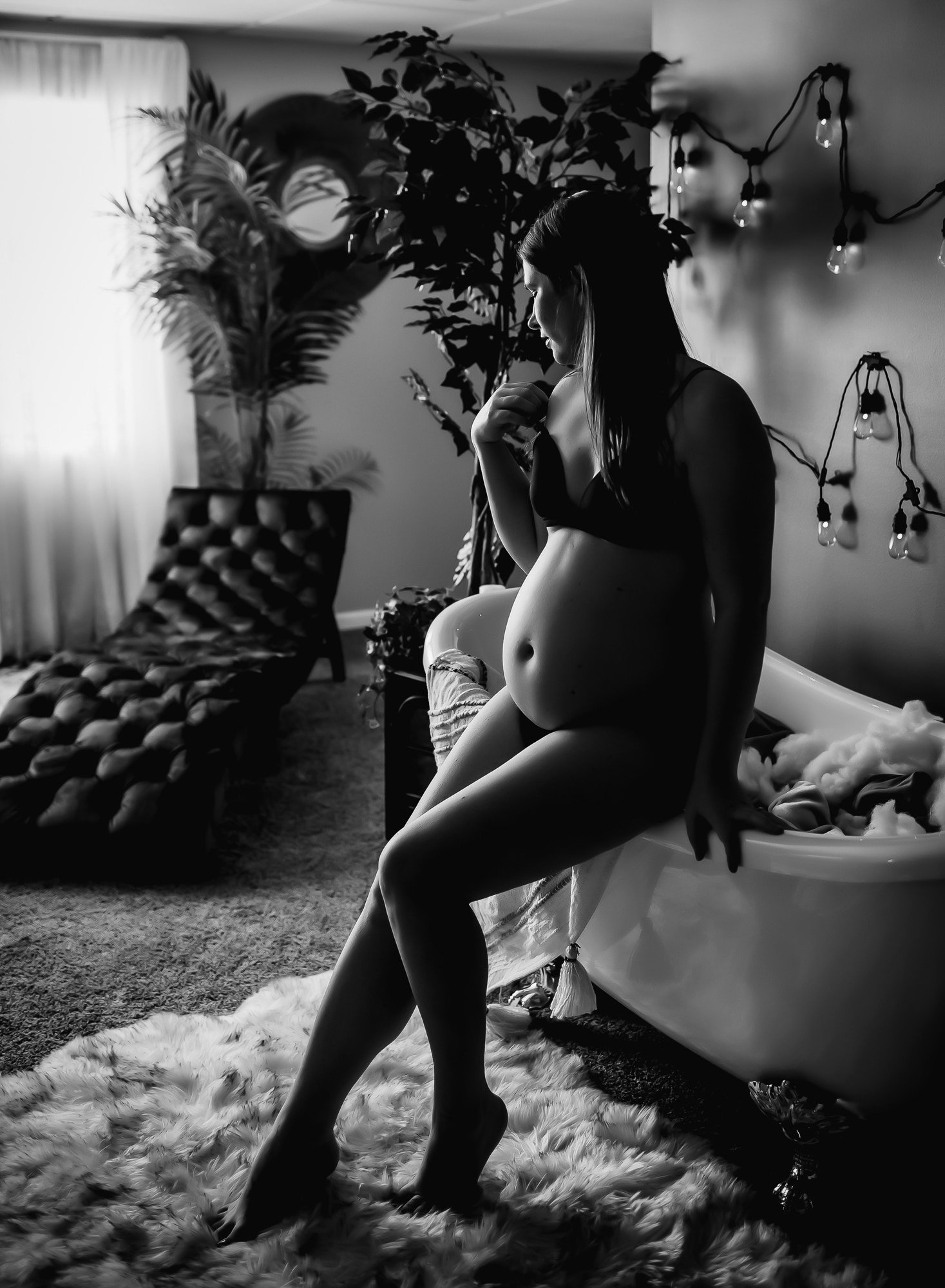 black-and-white-image-of-a-pregant-woman-sitting-on-edge-of-a-clawfoot-tub