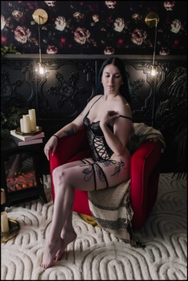 Image of a woman sitting in a red chair in black lingerie