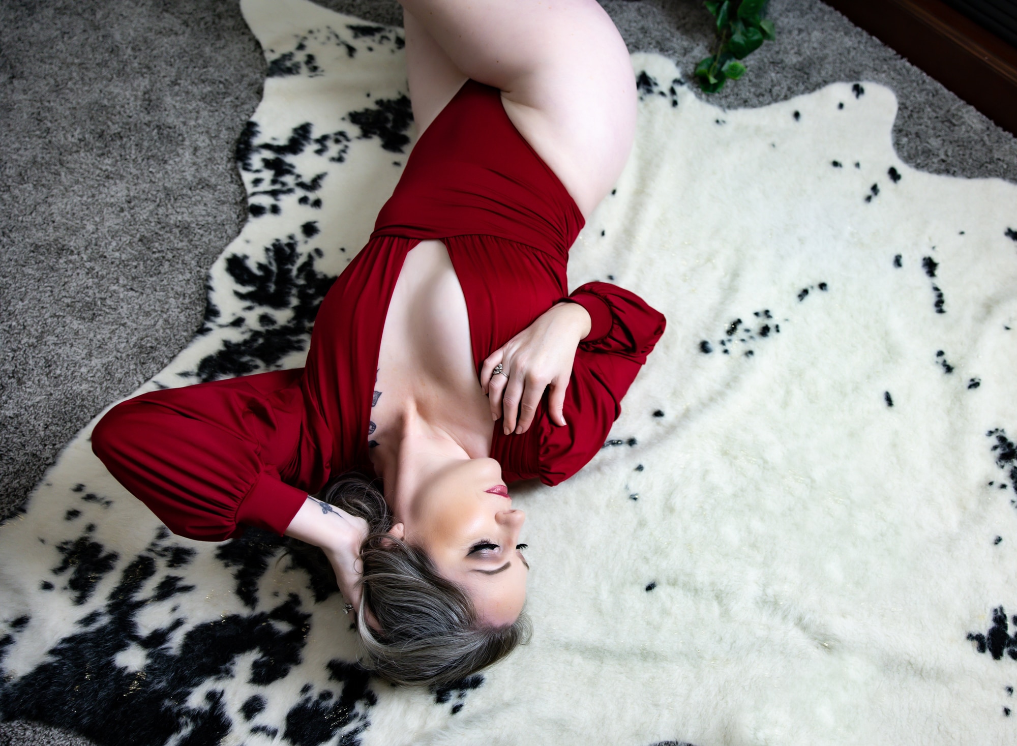 woman in red bodysuit on cow print rug