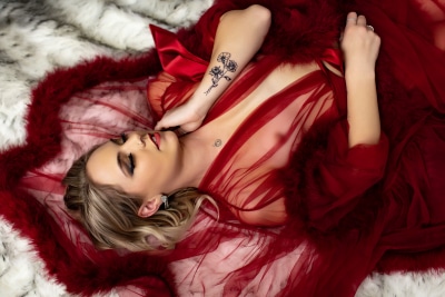 woman in red luxe robe laying on fur rug